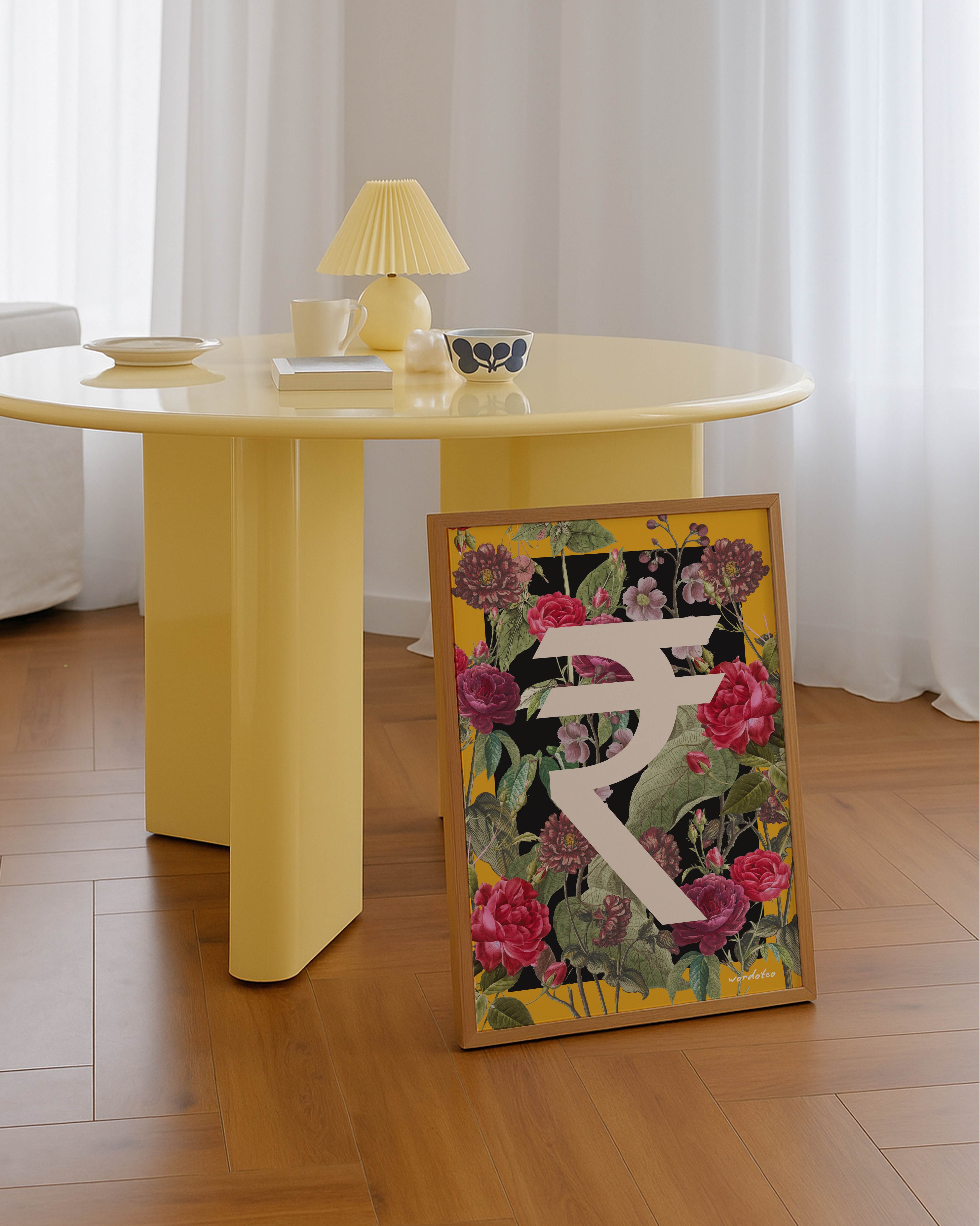 Yellow table with a decorative frame featuring a rupee symbol and flowers on a wooden floor.